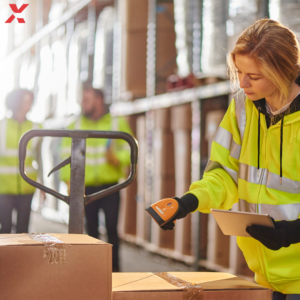 Une employée dans un entrepôt en train de contrôler des cartons pour rédiger son rapport.