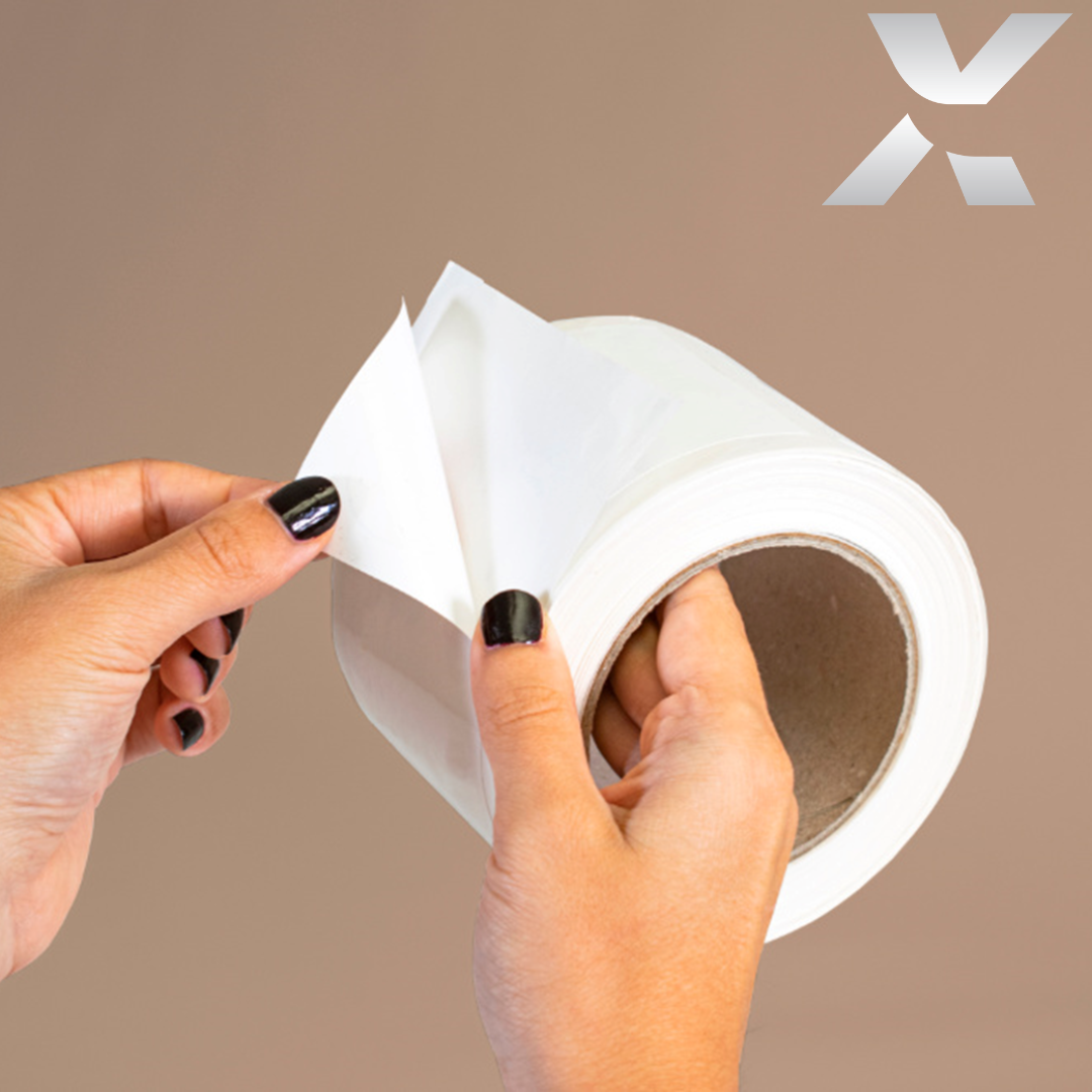 Une main tenant un rouleu d'étiquettes auto-collantes