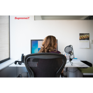 Une employée de SupremeX est assise à un bureau moderne, face à un écran d’ordinateur.
