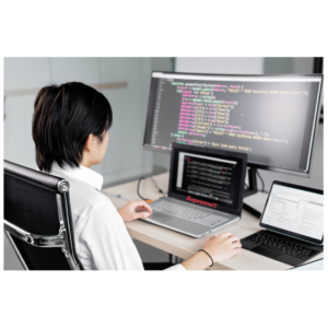 Un employé de SupremeX est assis dans un bureau moderne, travaillant sur plusieurs écrans affichant du code.